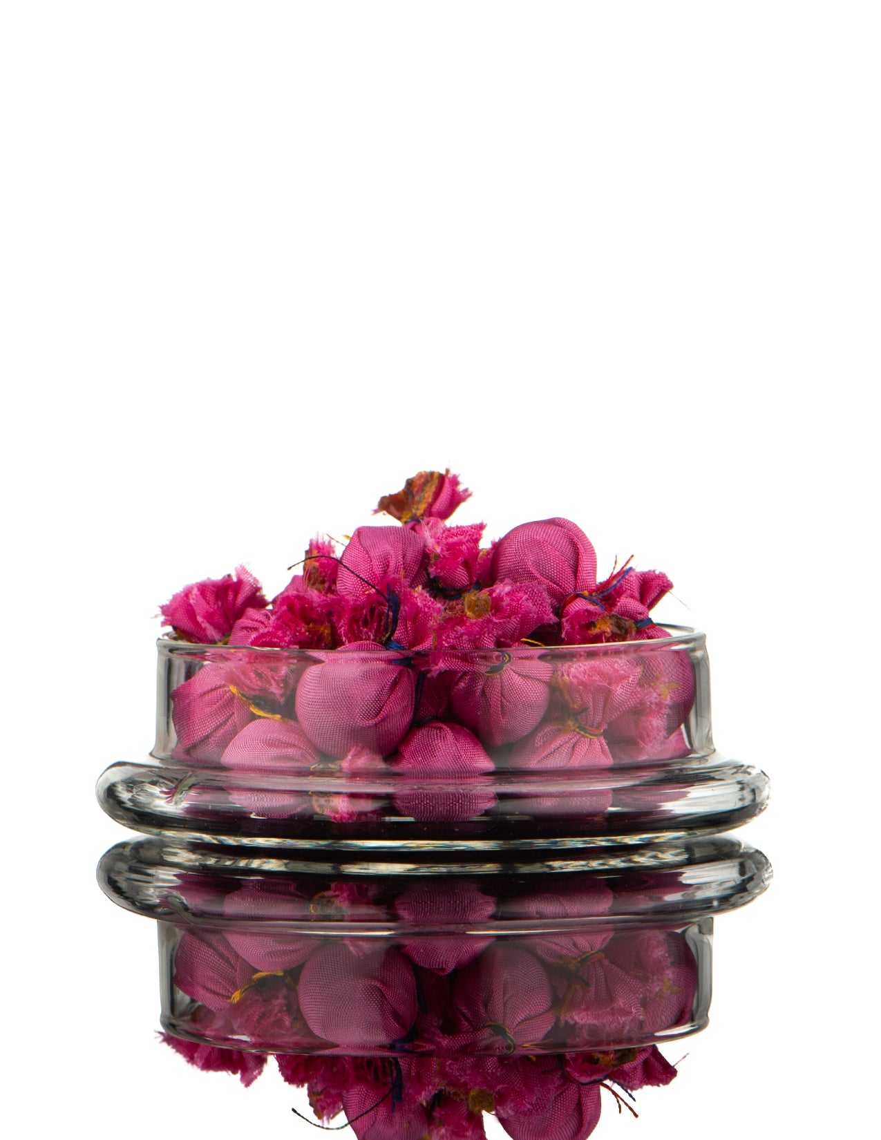 Glass container with pink pills on a white background